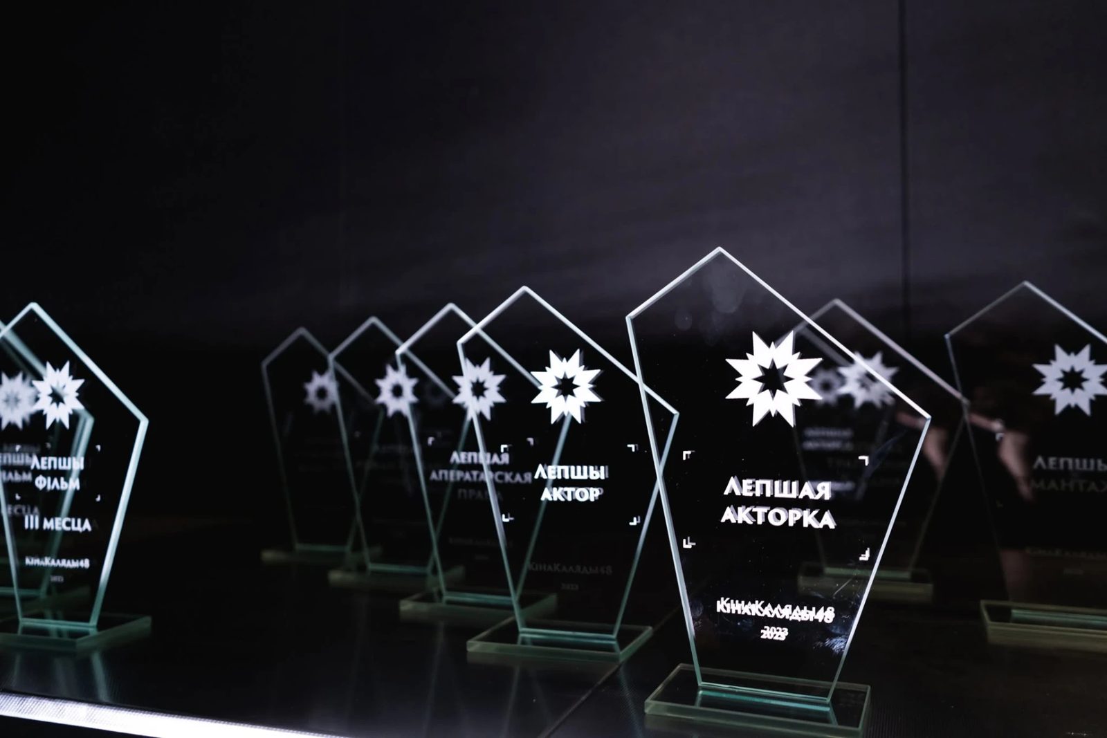 Glass KinaKaliady48 awards displayed on a lit table