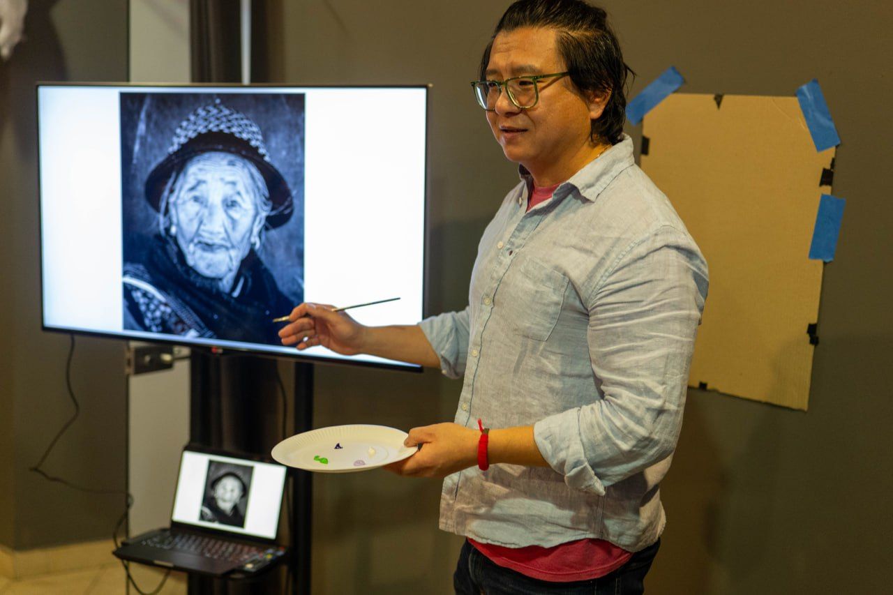 Artist presenting a black-and-white portrait during a workshop