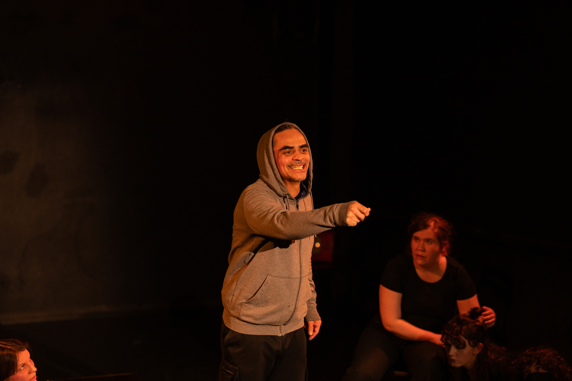 Performer in a grey hoodie pointing toward the audience during the show