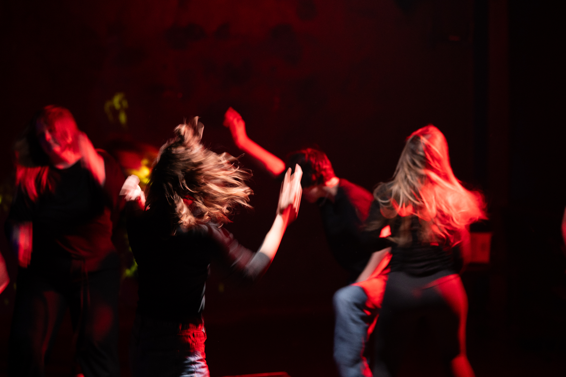 Dancers in motion on stage under red light