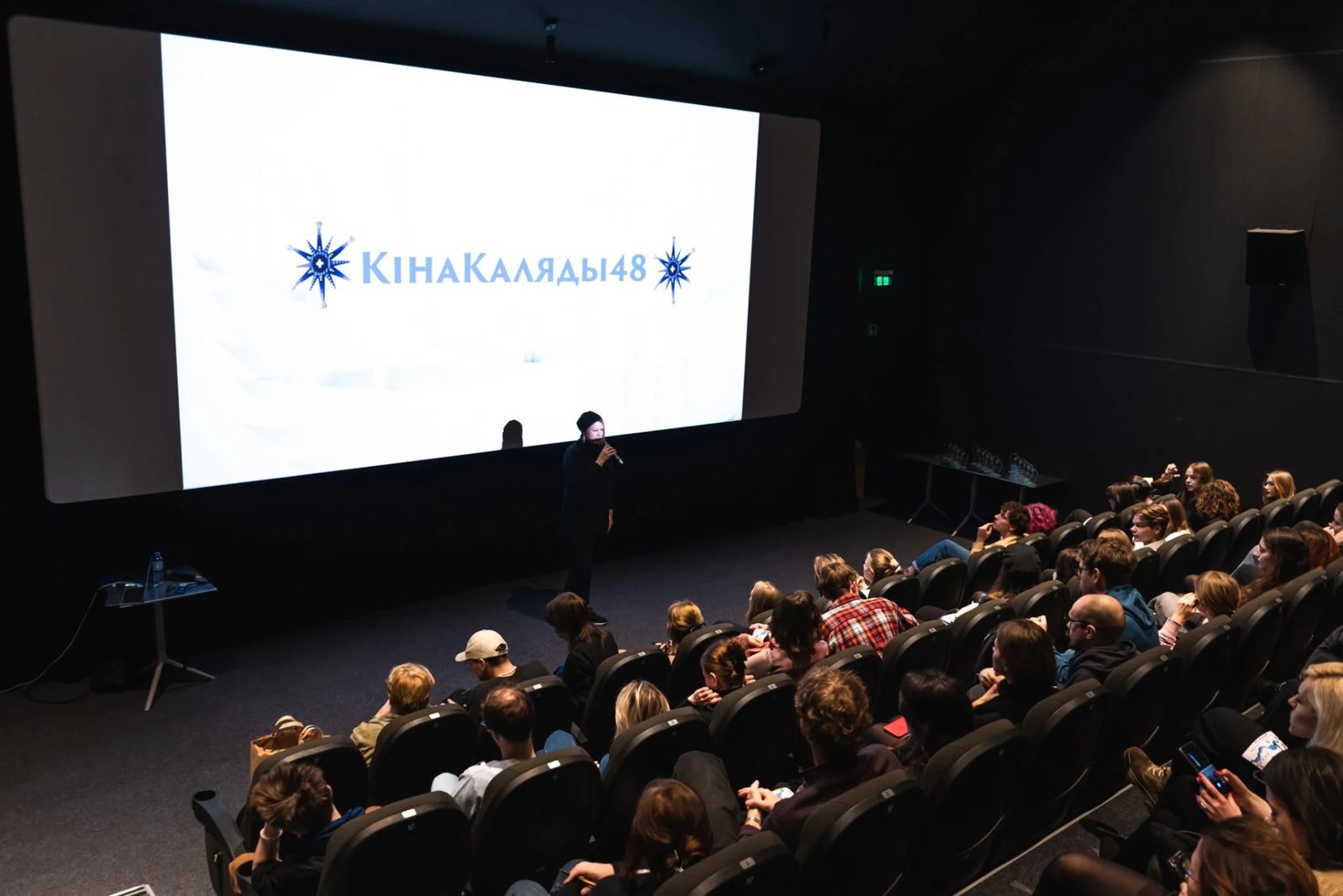 Host presenting a KinaKaliady48 screening to a full cinema audience