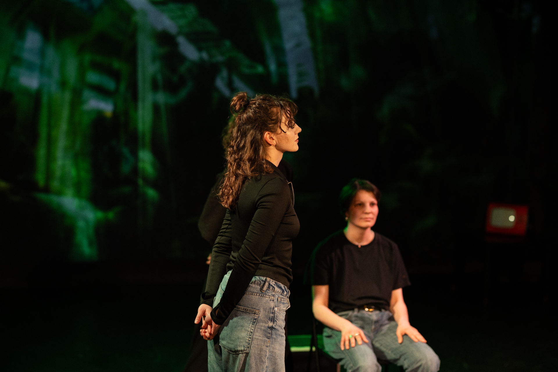 Performer standing on stage against a green projection backdrop