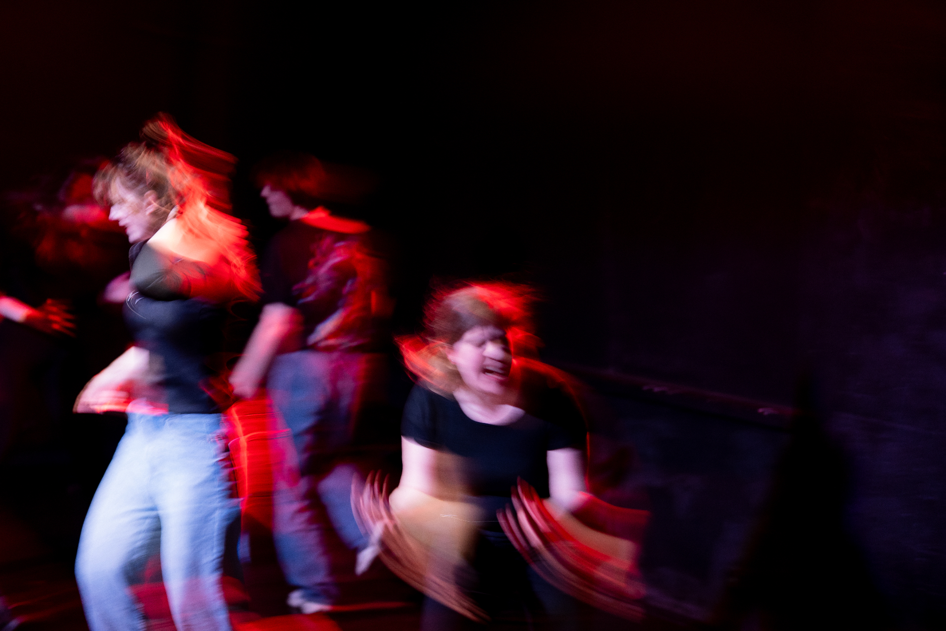 Performers moving energetically under red stage lighting