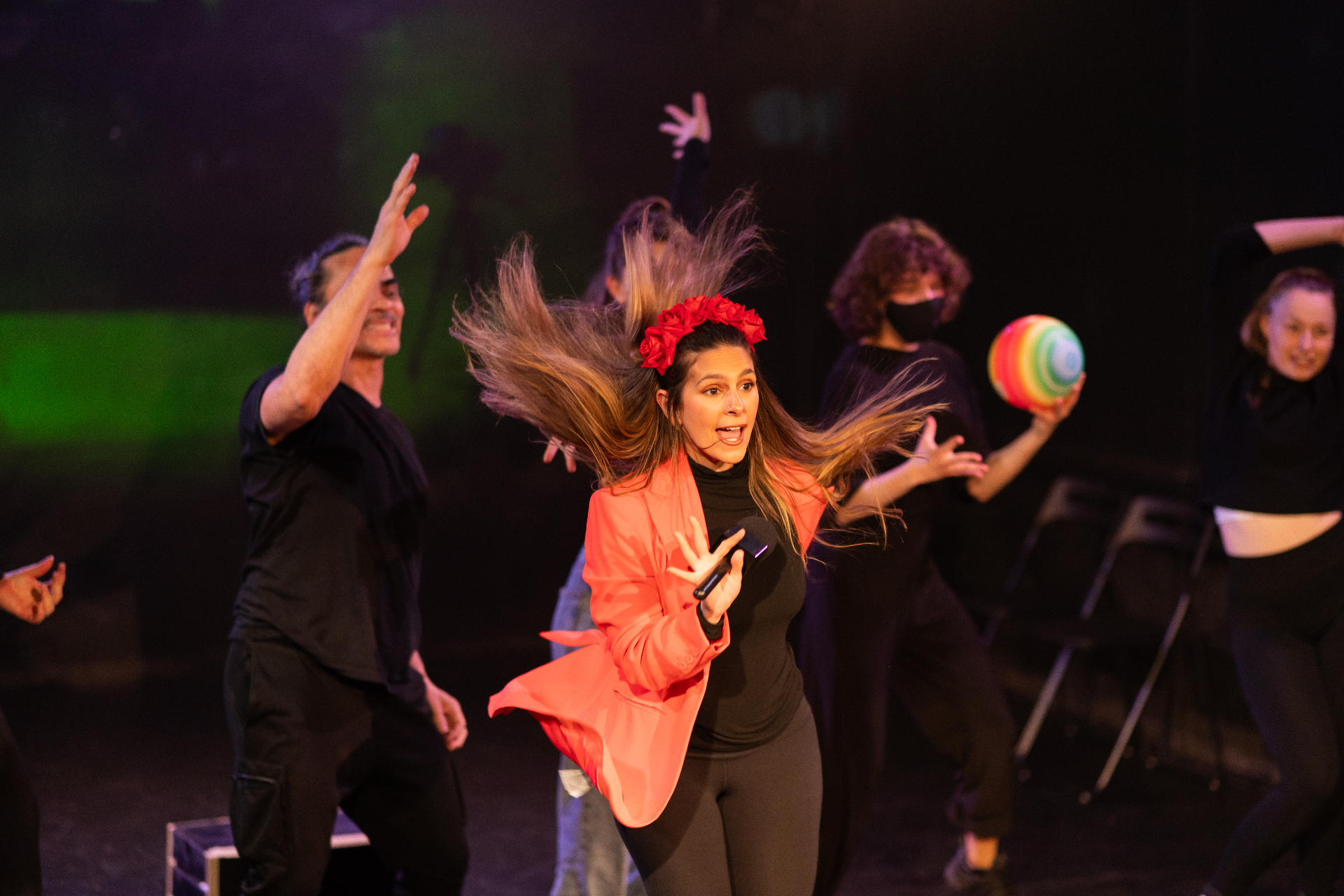 Performer singing centre stage with a red flower crown
