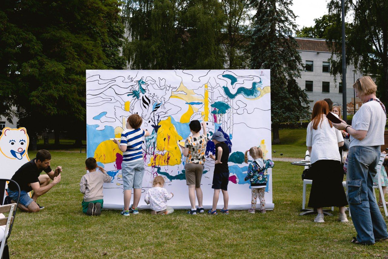 Children painting a large collaborative mural in a park
