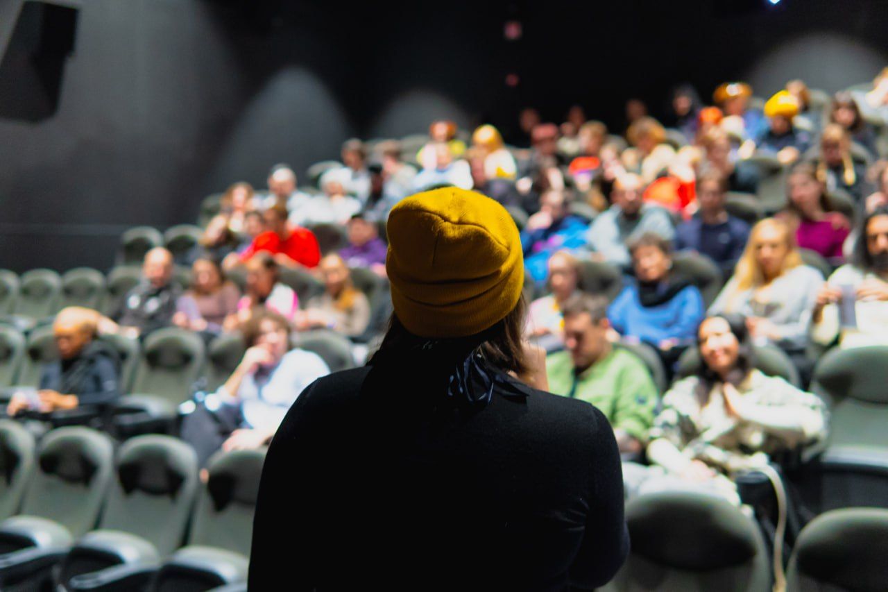 Speaker addressing a full cinema audience